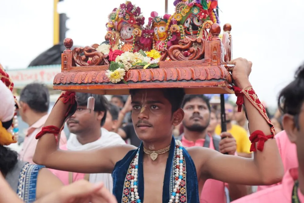 A devotee carrying the deities of Jagannath, Balabhadra and Subhadra during a festival procession in Puri